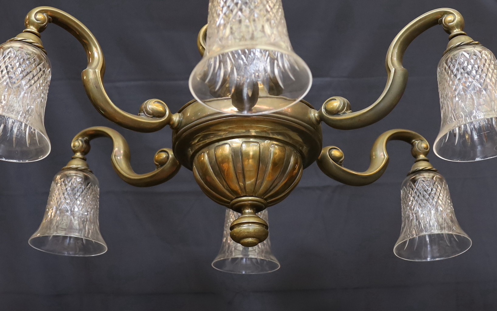 An early 20th century English bronze six light chandelier with cut glass shades, drop 70cm. width 80cm